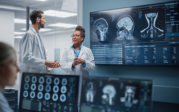 Medical Hospital Health Care Lab: Camera Captures Professional Neuroscientists Analysing CT Scan Finding Cure for Sick Patient and Female Neurologists Using Computer with Brain Scan MRI Images