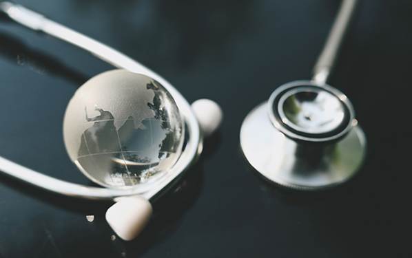 Globe de verre représentant la Terre et un stéthoscope posés sur une table.